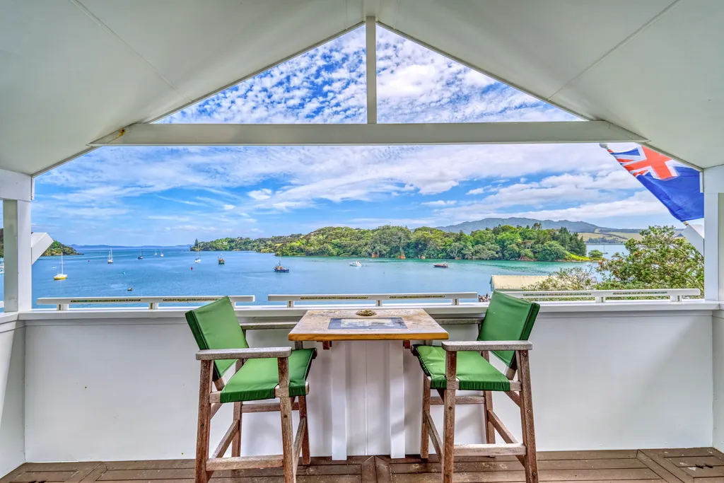 Covered balcony with two green chairs overlooking a sheltered bay with moored boats