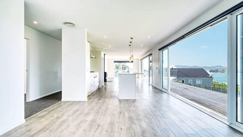Light-filled open-plan living area with sliding doors to a deck and sea views